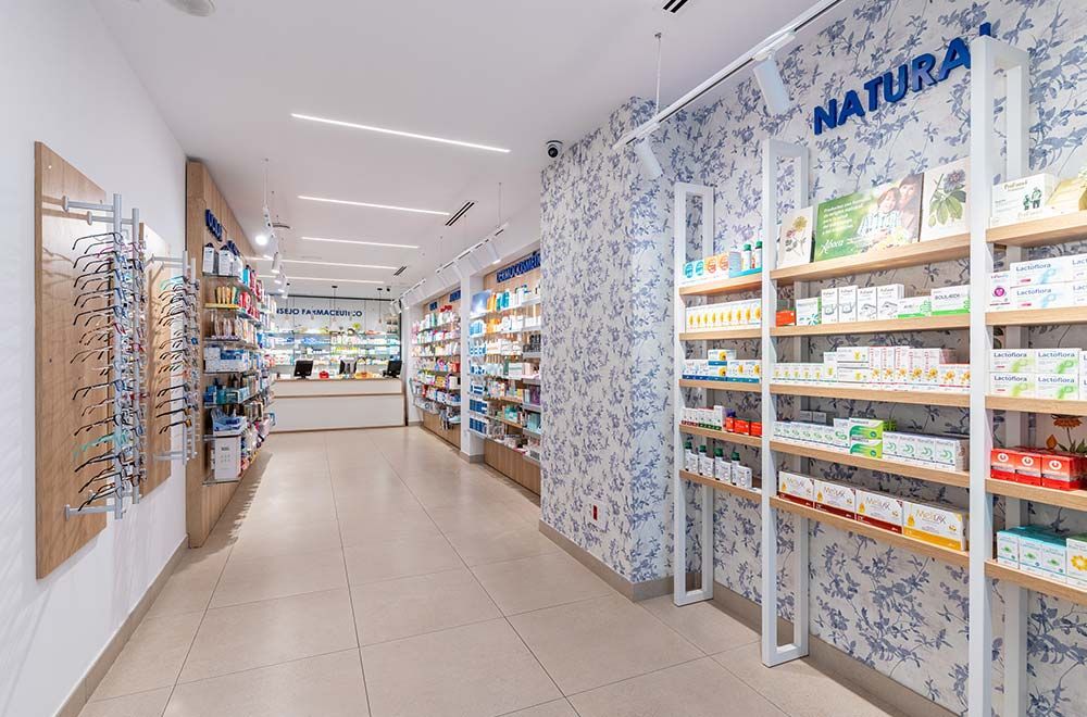 Un largo pasillo en una farmacia con muchos estantes y un mostrador.