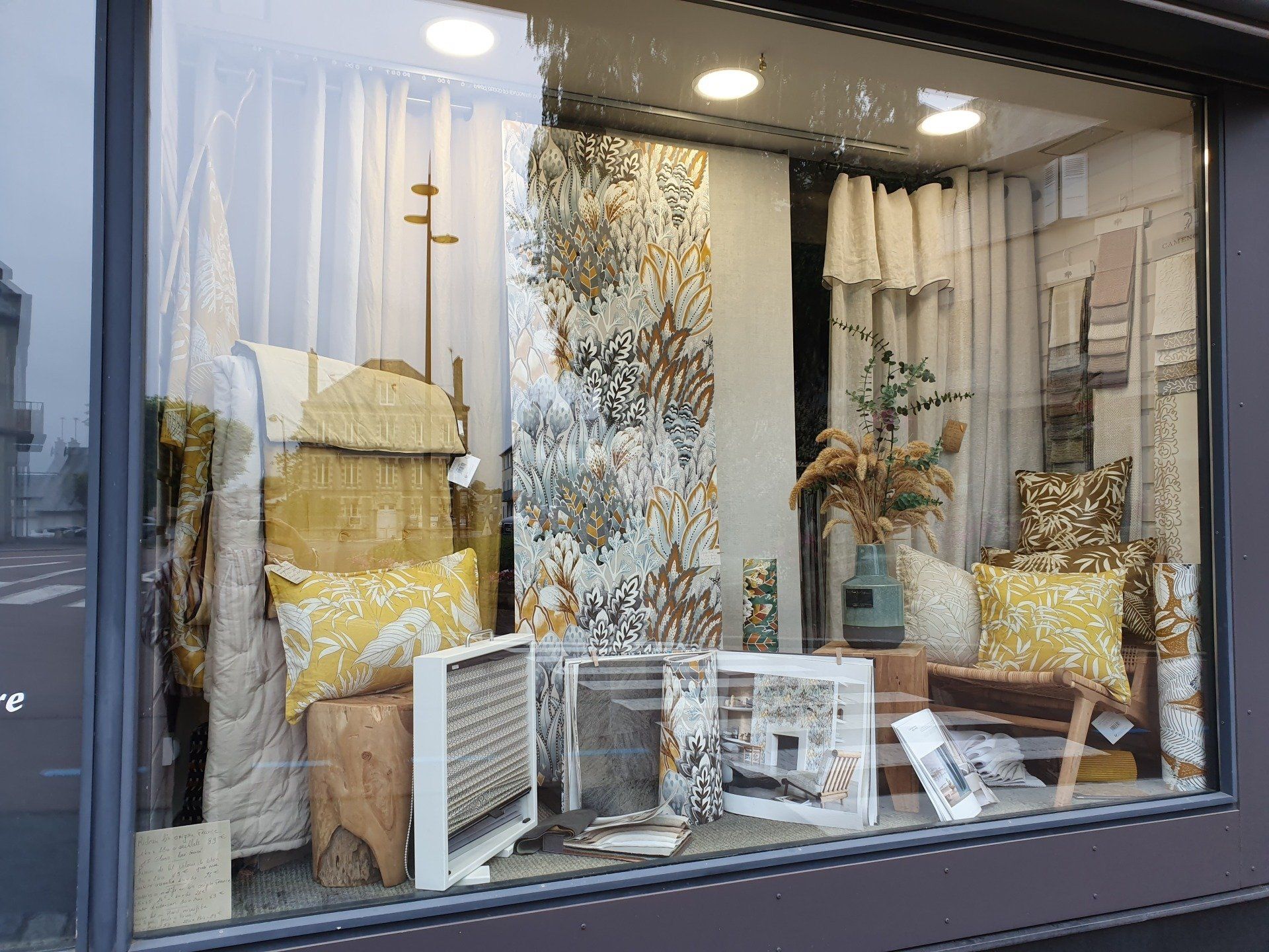 Vitrine avec des tissus à motifs jaunes et blancs et des éléments décoratifs.