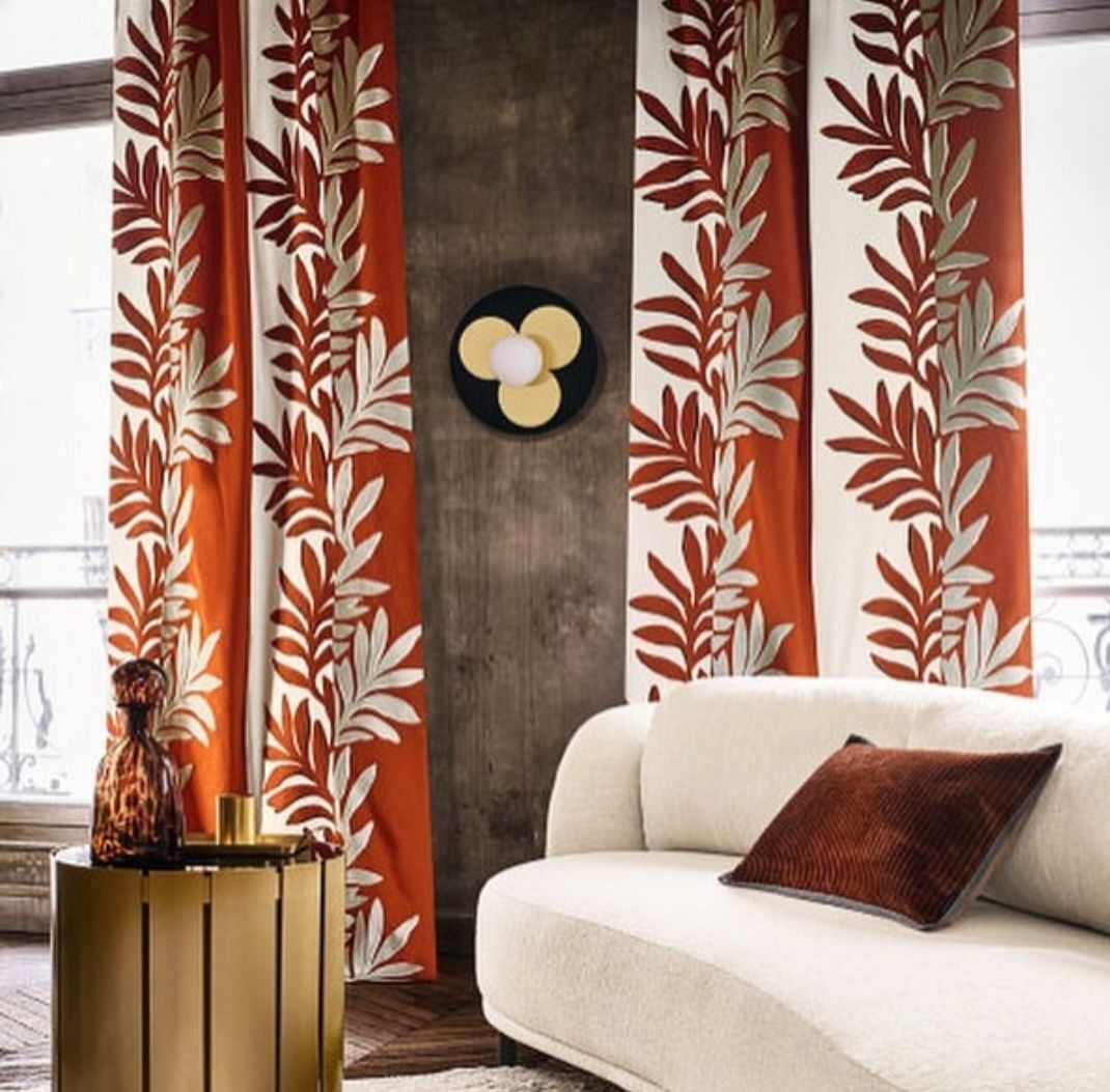 Canapé blanc avec coussin marron devant rideau beige et rouge