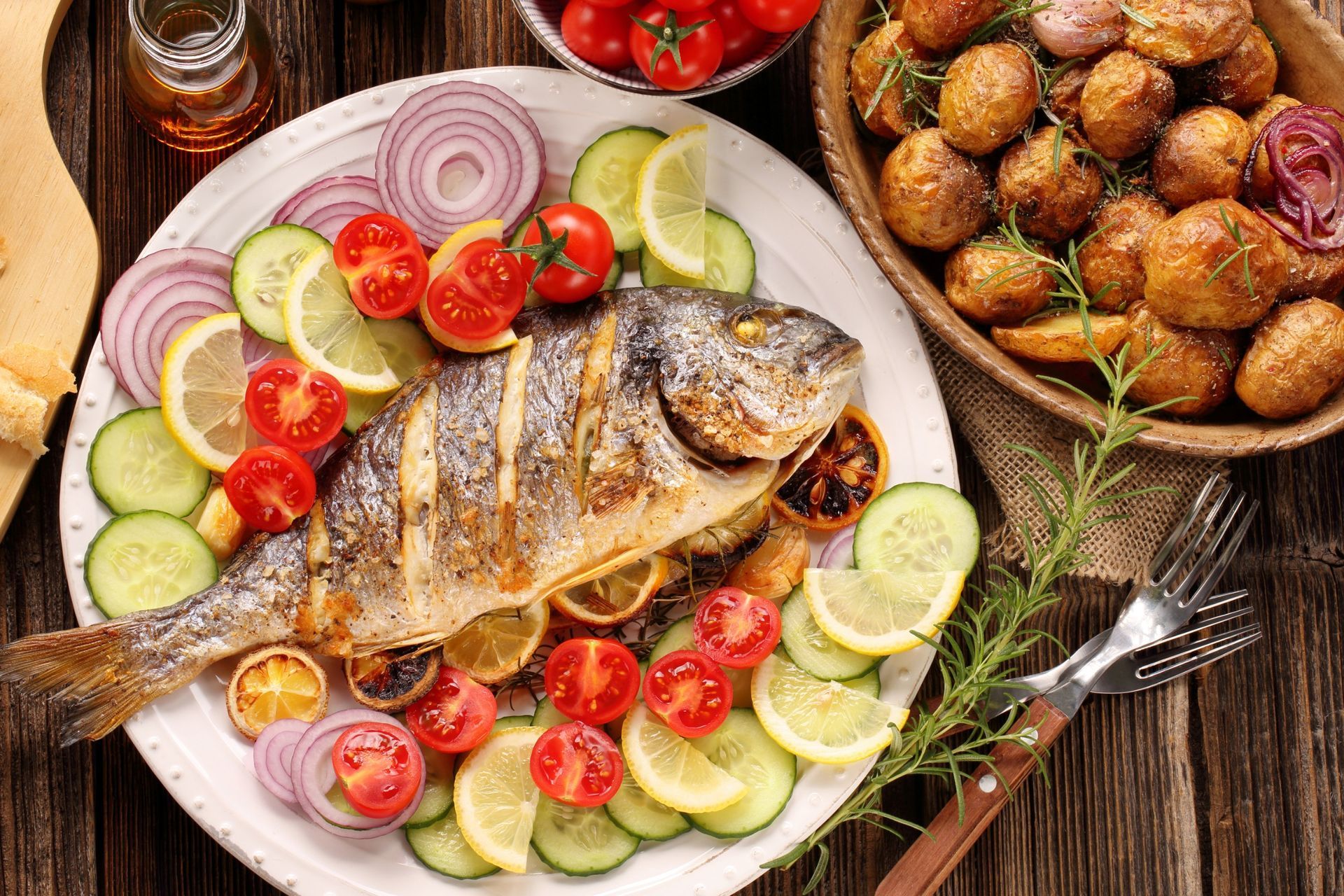 Un plato blanco cubierto con pescado y verduras sobre una mesa de madera.