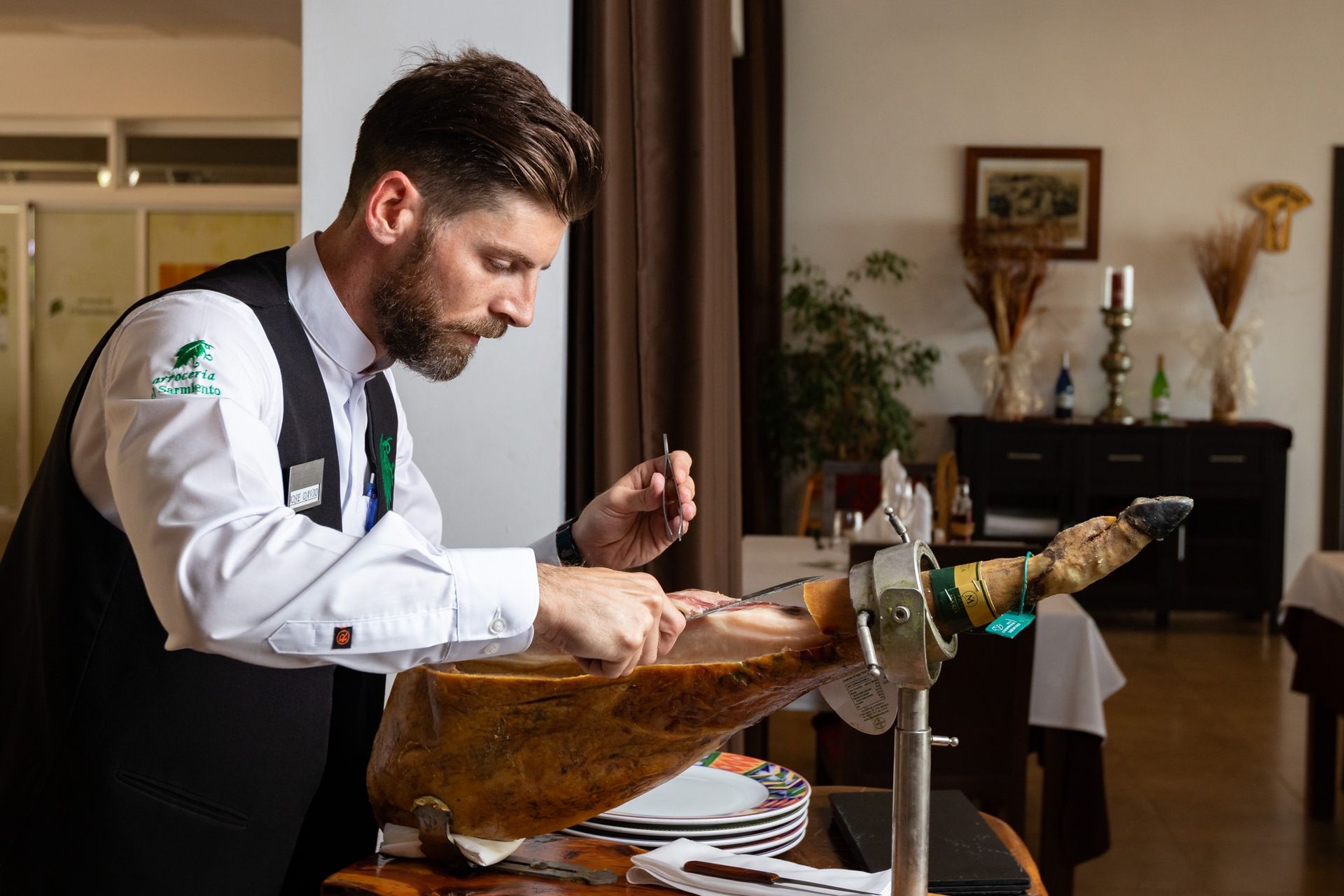 Un hombre está cortando un trozo de carne en una mesa en un restaurante.