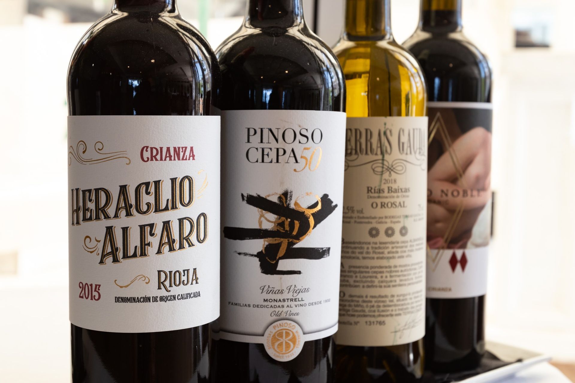 Cuatro botellas de vino están alineadas una al lado de la otra en una mesa.