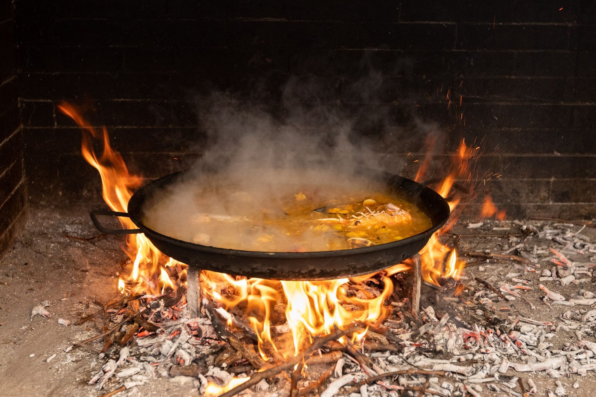 Una sartén con comida se está cocinando al fuego en una chimenea.