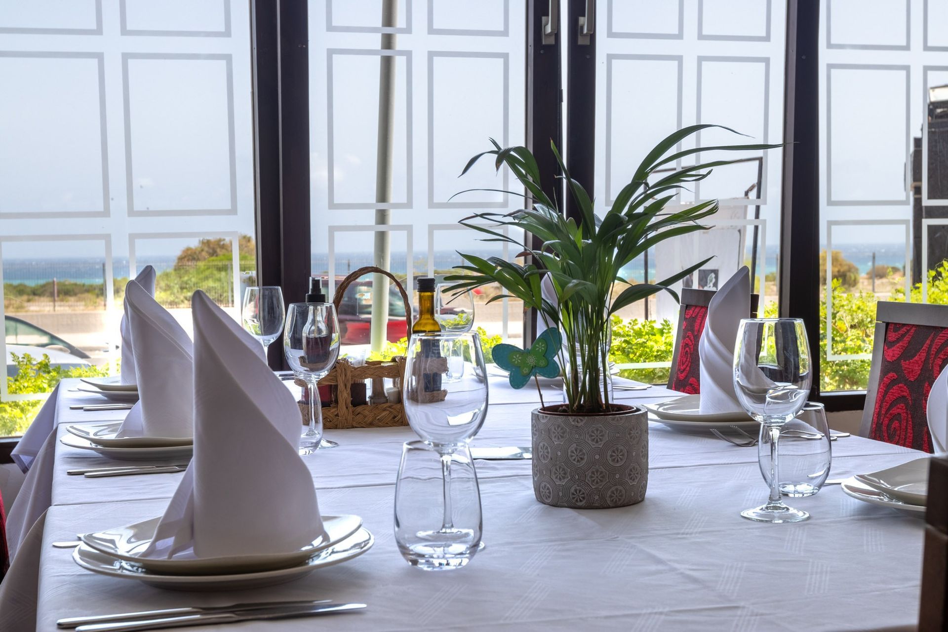 Una mesa de restaurante con platos, vasos, servilletas y una planta encima.