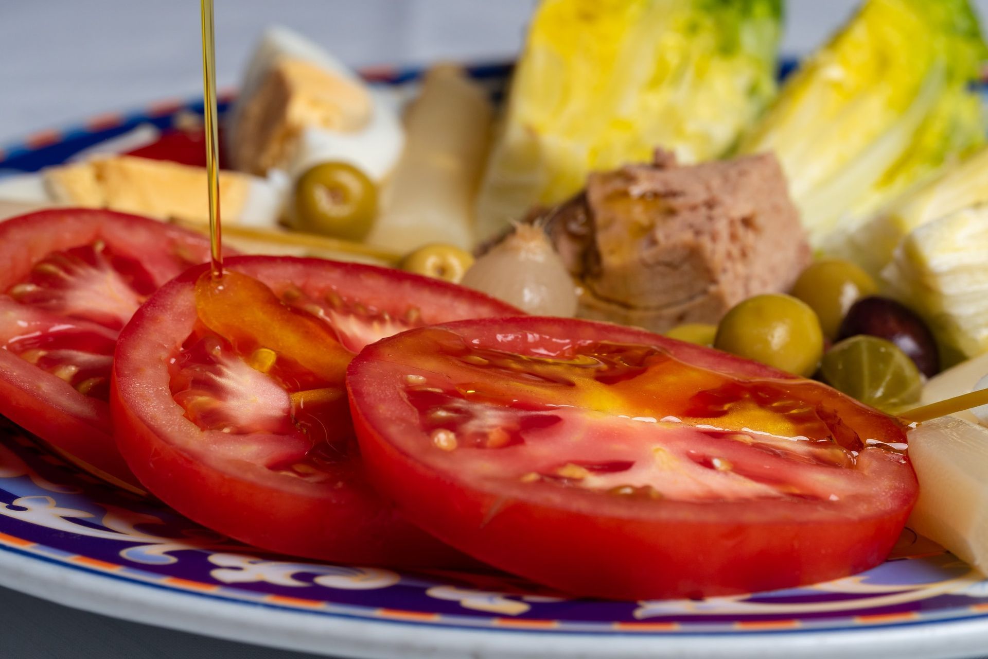 Un primer plano de un plato de comida con tomates y aceitunas encima.