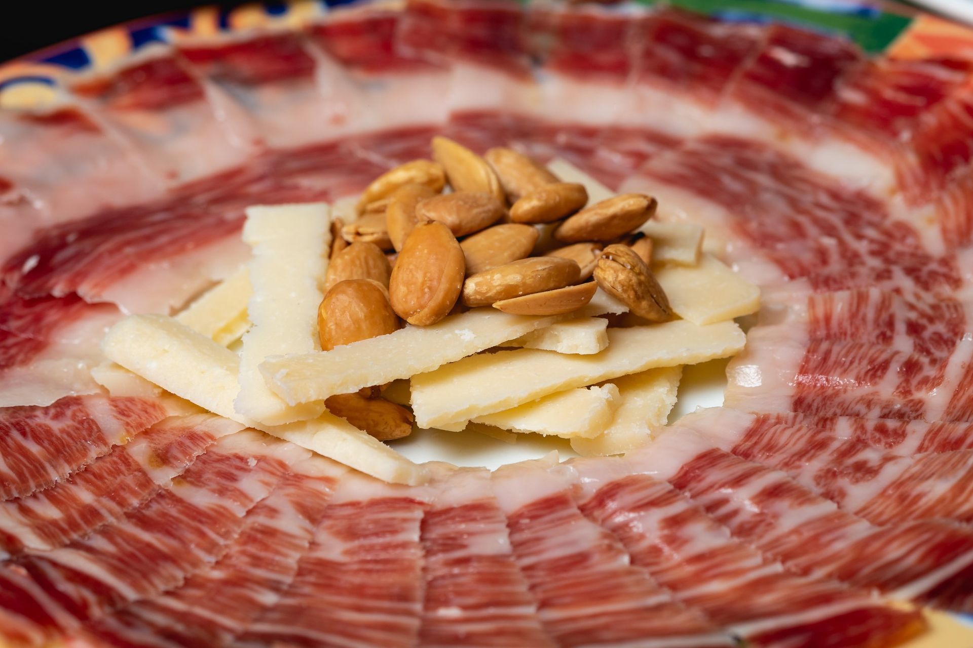 Un plato de carne y queso con almendras encima.