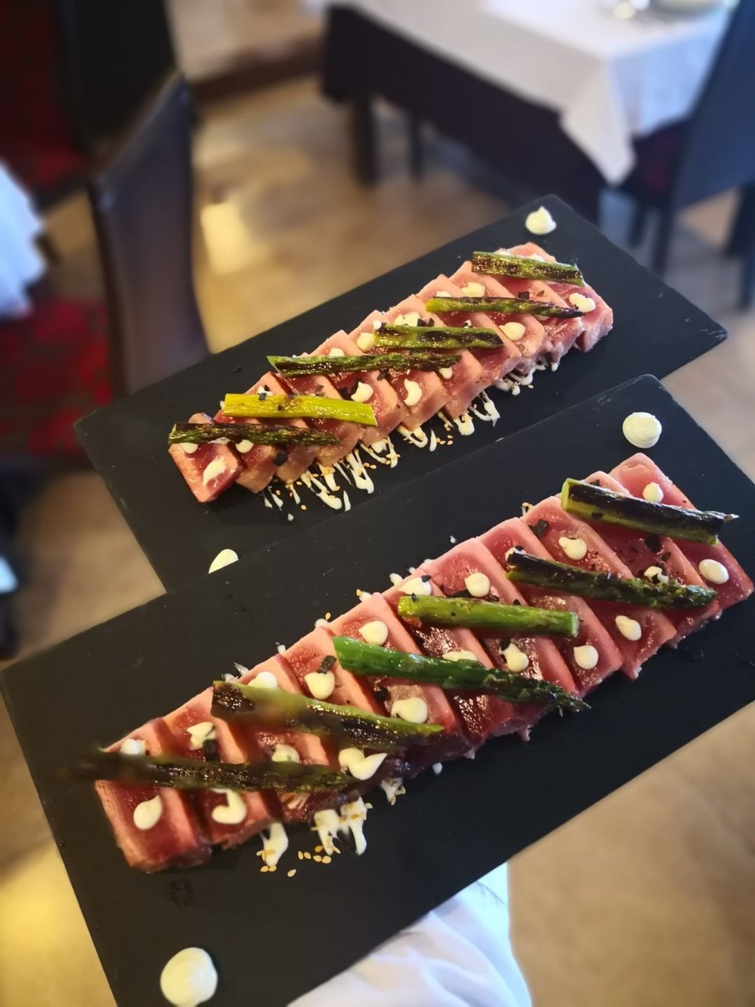 Una persona sostiene dos platos de comida con espárragos encima.