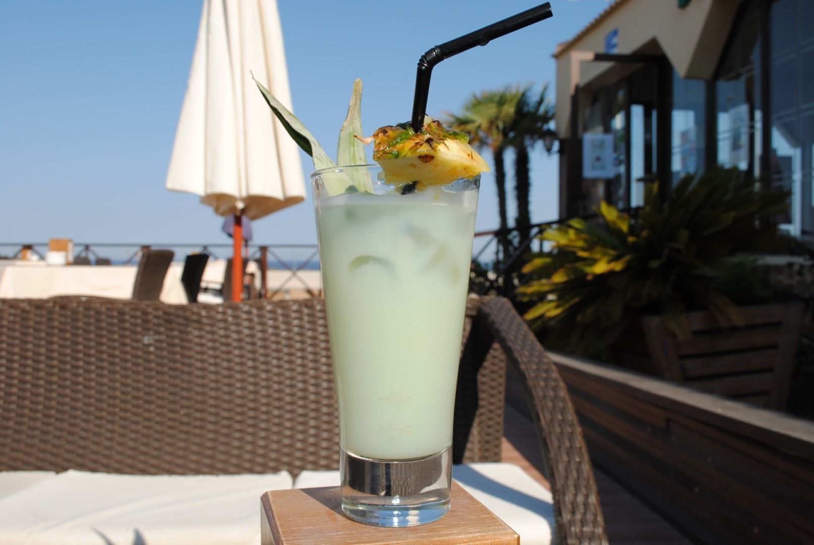 Un vaso alto de líquido verde con una piña encima.