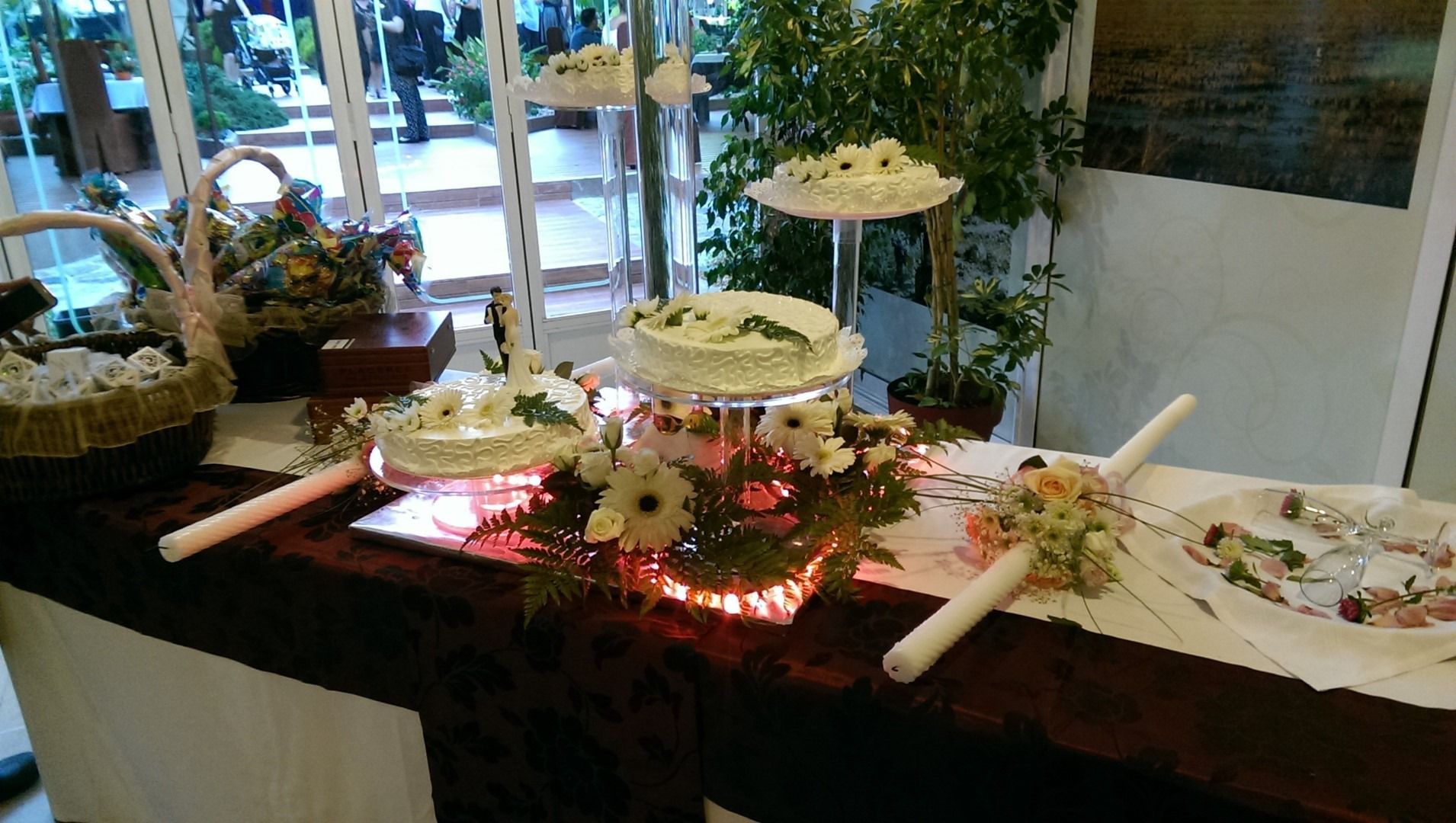 Una mesa con tres pasteles y flores encima.