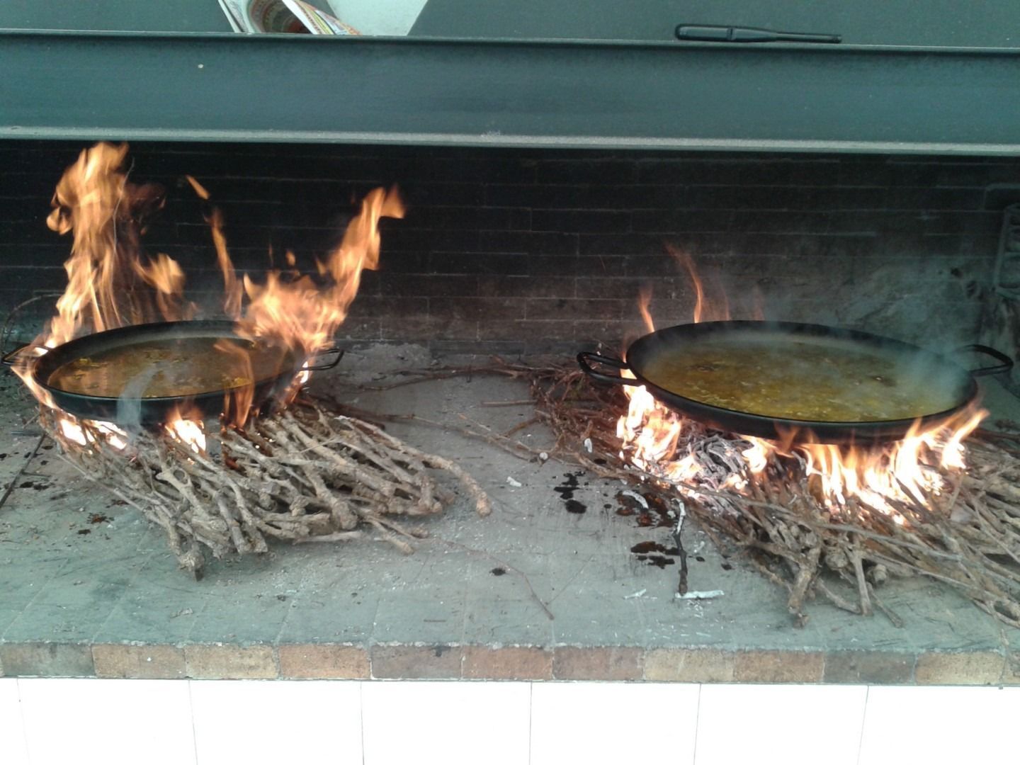 Dos sartenes se están cocinando sobre el fuego en una chimenea.