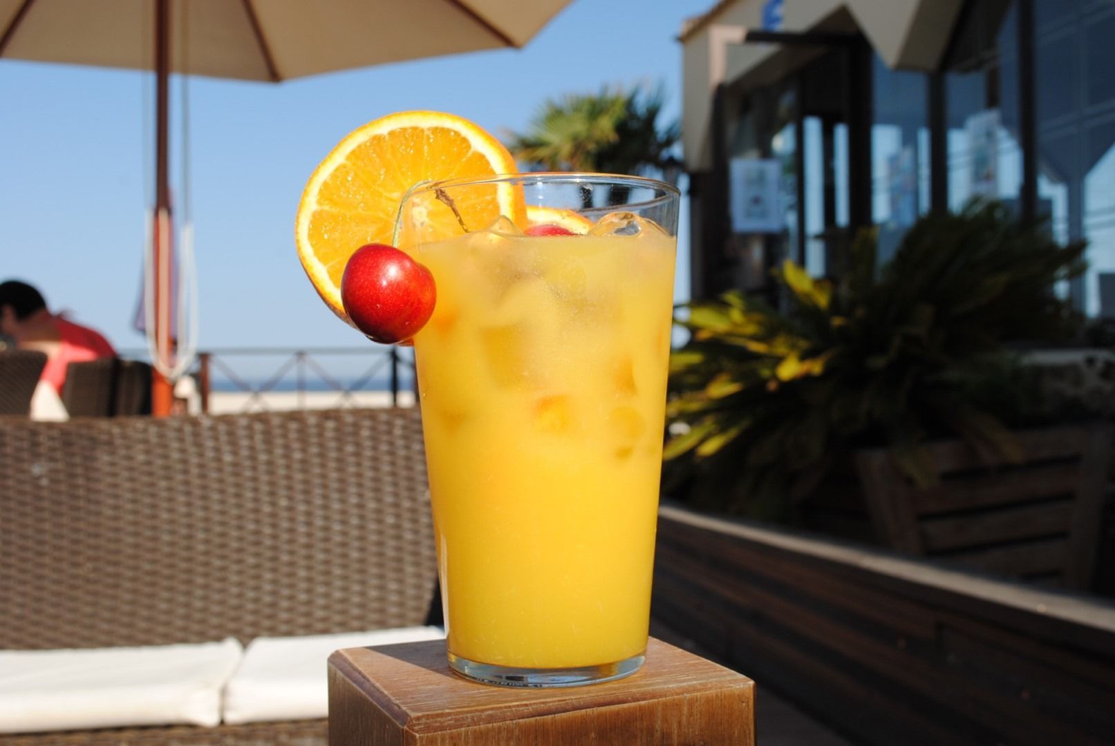 Un vaso de jugo de naranja con una cereza encima