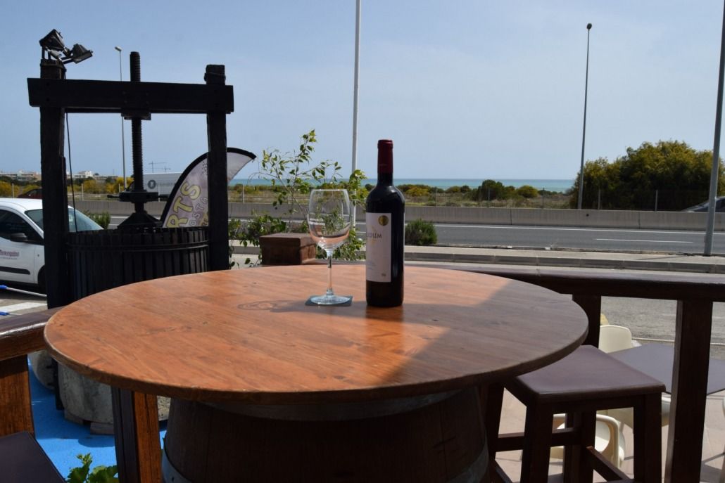 Una botella de vino reposa sobre una mesa de madera junto a un vaso.