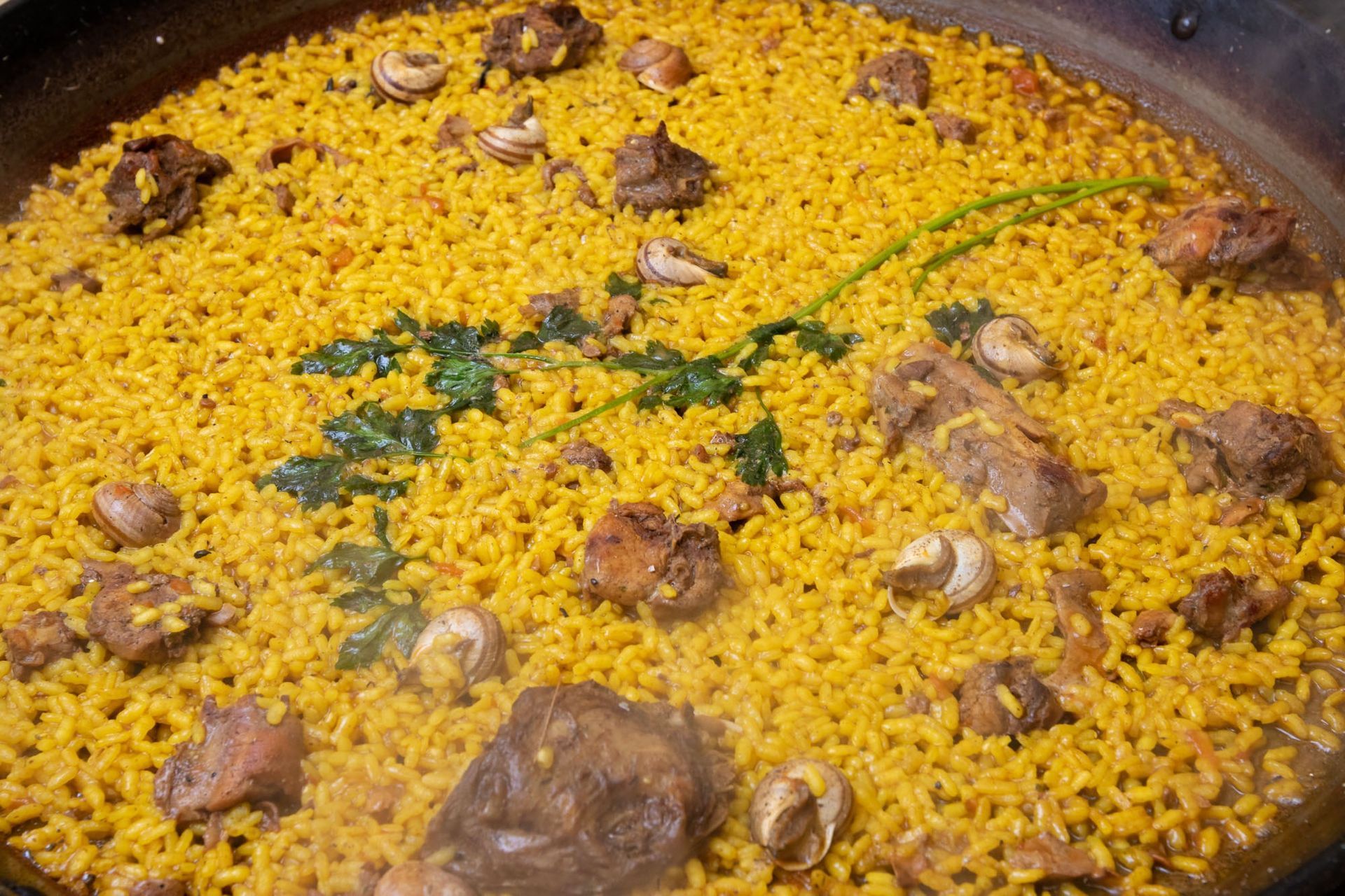 Se está cocinando una sartén llena de arroz y carne.