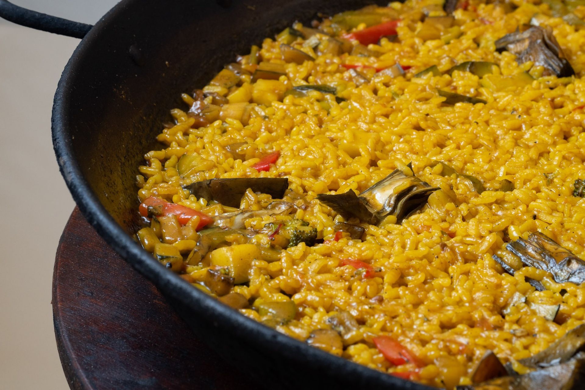 Una sartén llena de arroz y verduras está sobre una mesa de madera.
