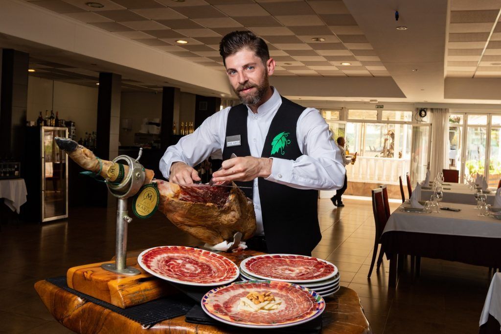 Un hombre está cortando un jamón en un restaurante.