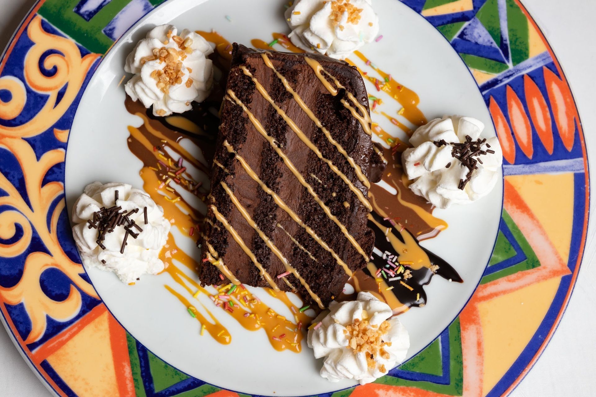 Un plato blanco cubierto con un trozo de pastel de chocolate y crema batida.