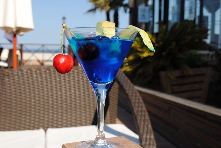 Un martini azul con una cereza encima.
