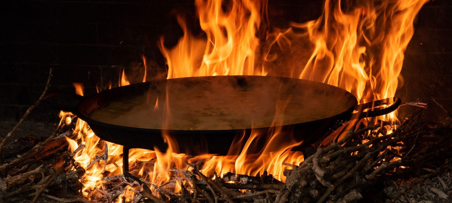 Una sartén se está cocinando al fuego en una chimenea.