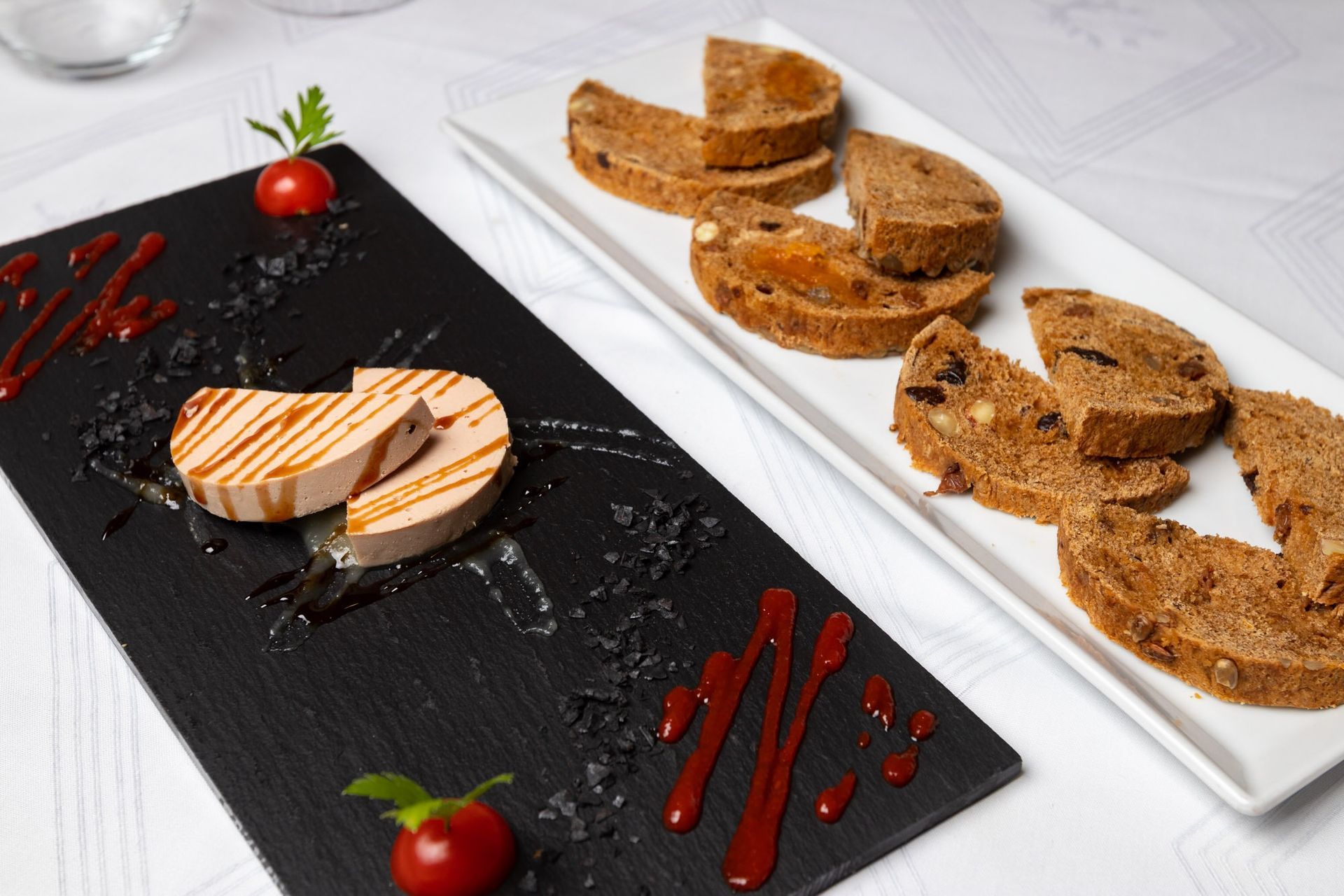 Dos platos de comida en una mesa con tomates encima.