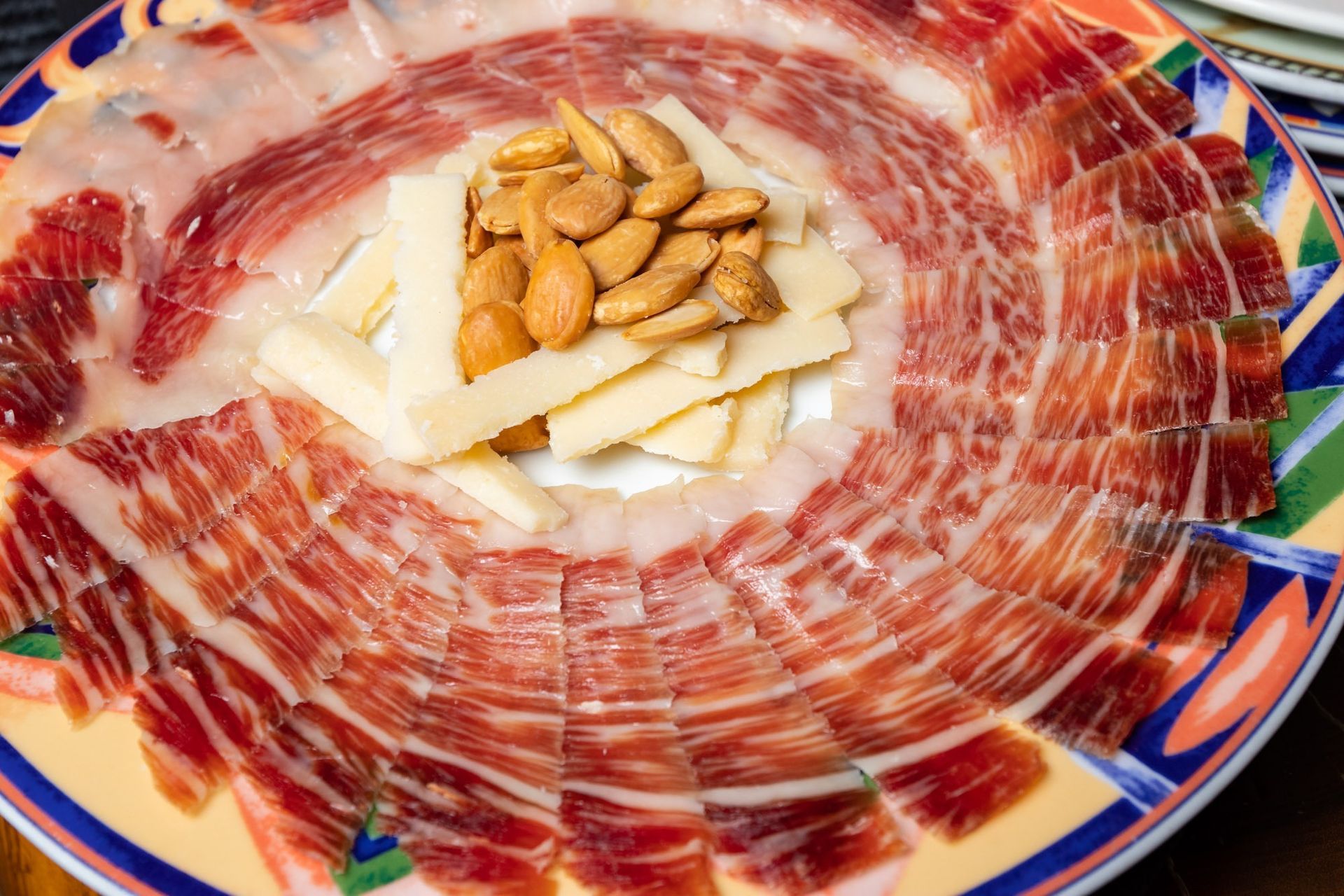 Un plato de carne y queso con almendras encima.