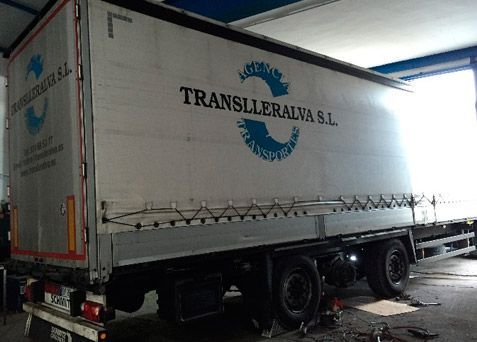 Camión semirremolque Translleras SL blanco estacionado en el interior de un muelle de carga.