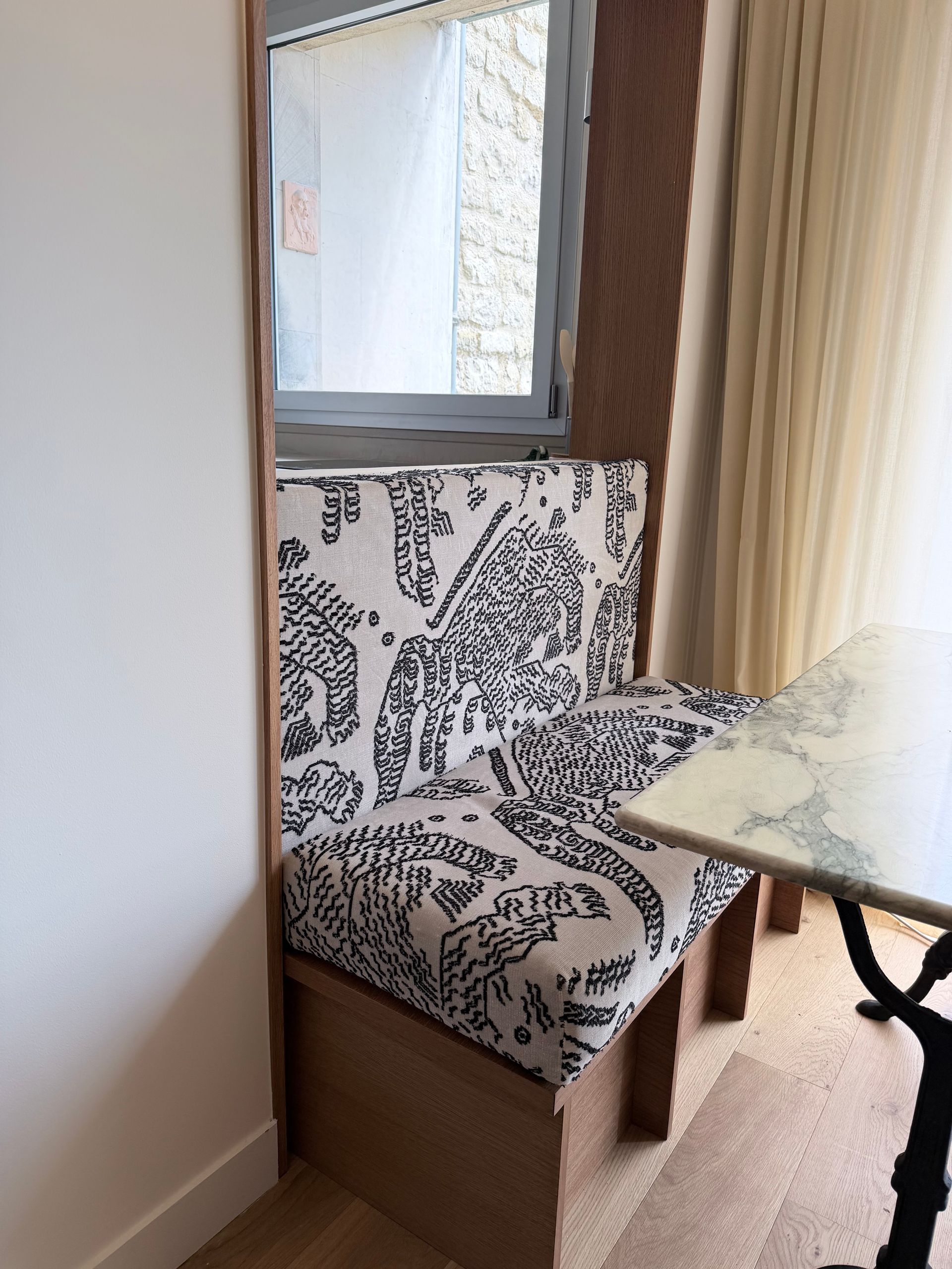Chaise à motifs près d'une fenêtre, à côté d'une petite table dans une pièce lumineuse