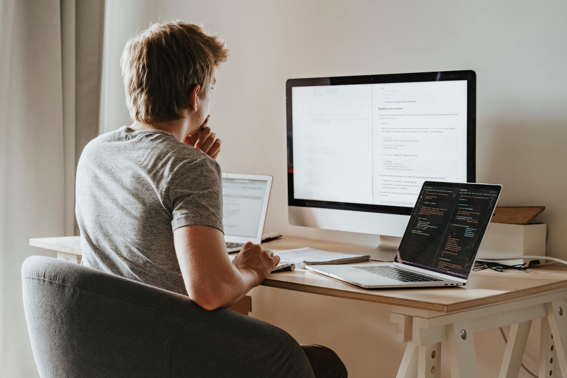 A man is sitting at a desk with a laptop and a computer.