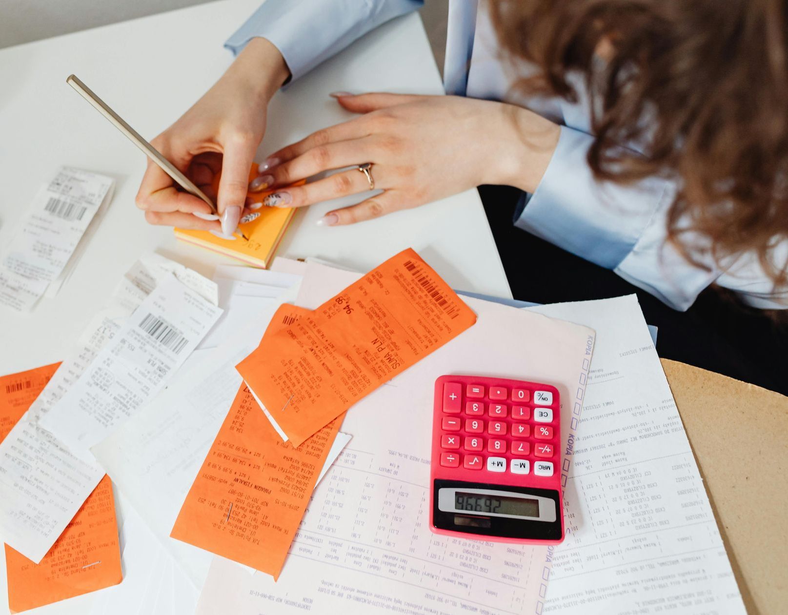 A woman is sitting at a table with receipts and a calculator.