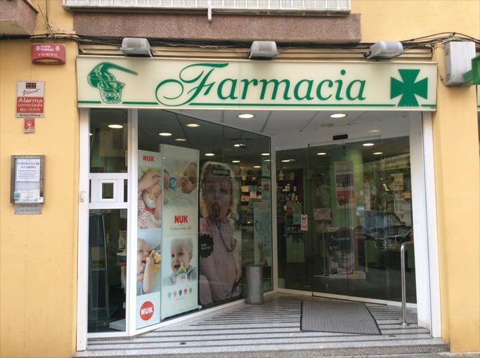 El frente de una farmacia con una cruz verde encima.