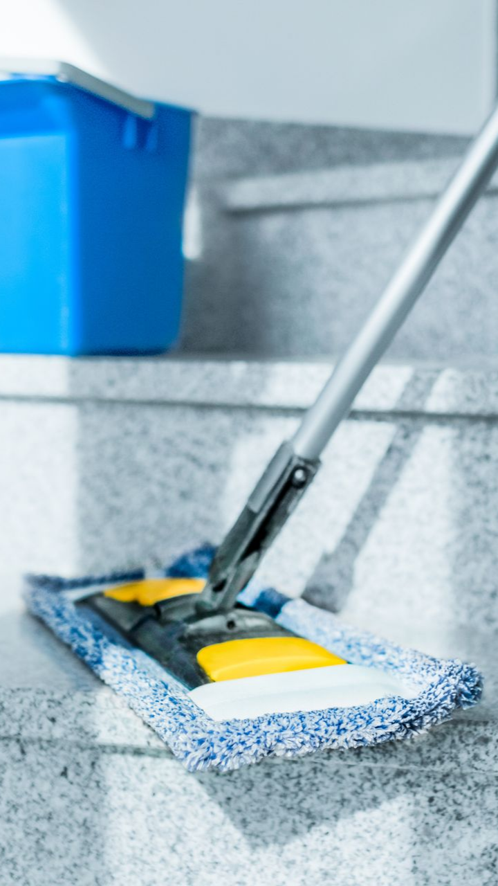 Une serpillière sur des marches en granit avec un seau bleu en arrière-plan.