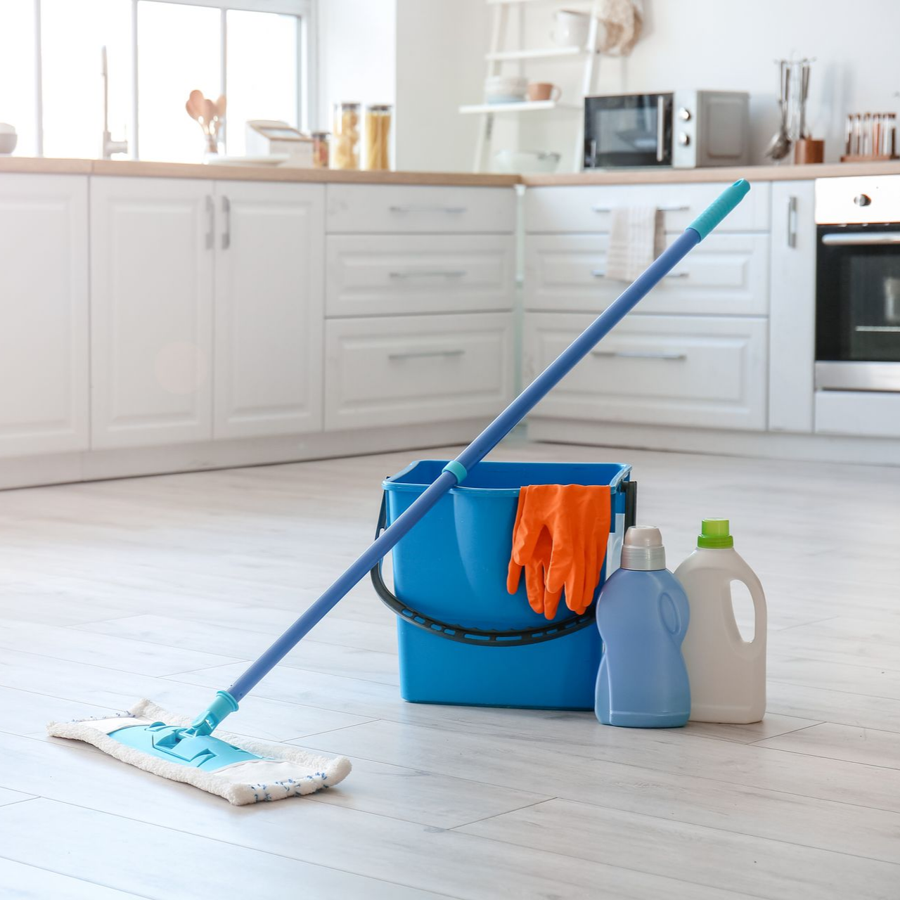 Balai-serpillière, seau, produits de nettoyage sur le sol de la cuisine.