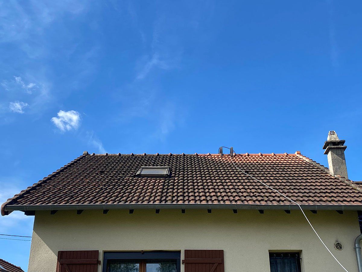 Toit d'une maison avec beaucoup de mousse sur les tuiles