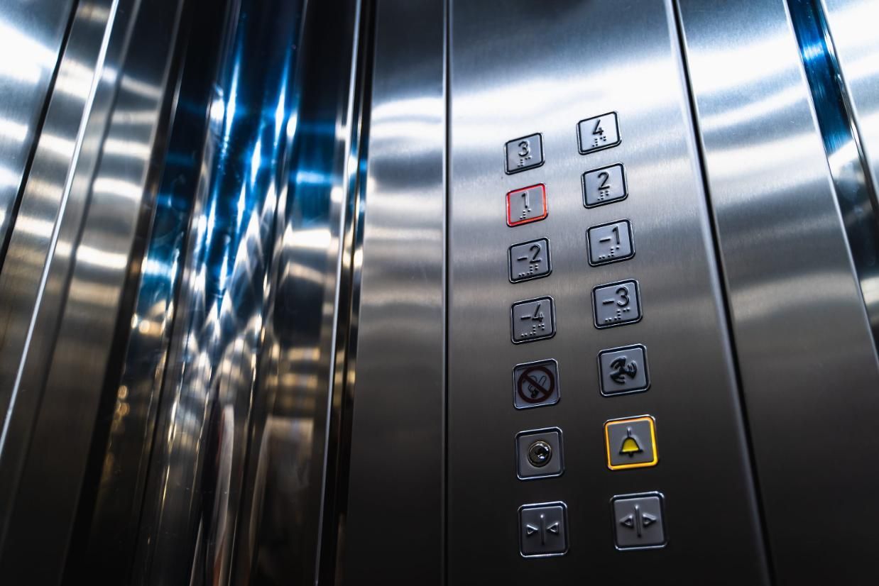 Panel de control del ascensor con botones de piso iluminados y paredes reflectantes de acero inoxidable.