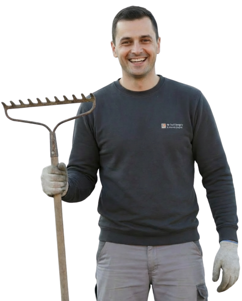 Un artisan souriant tient un râteau.