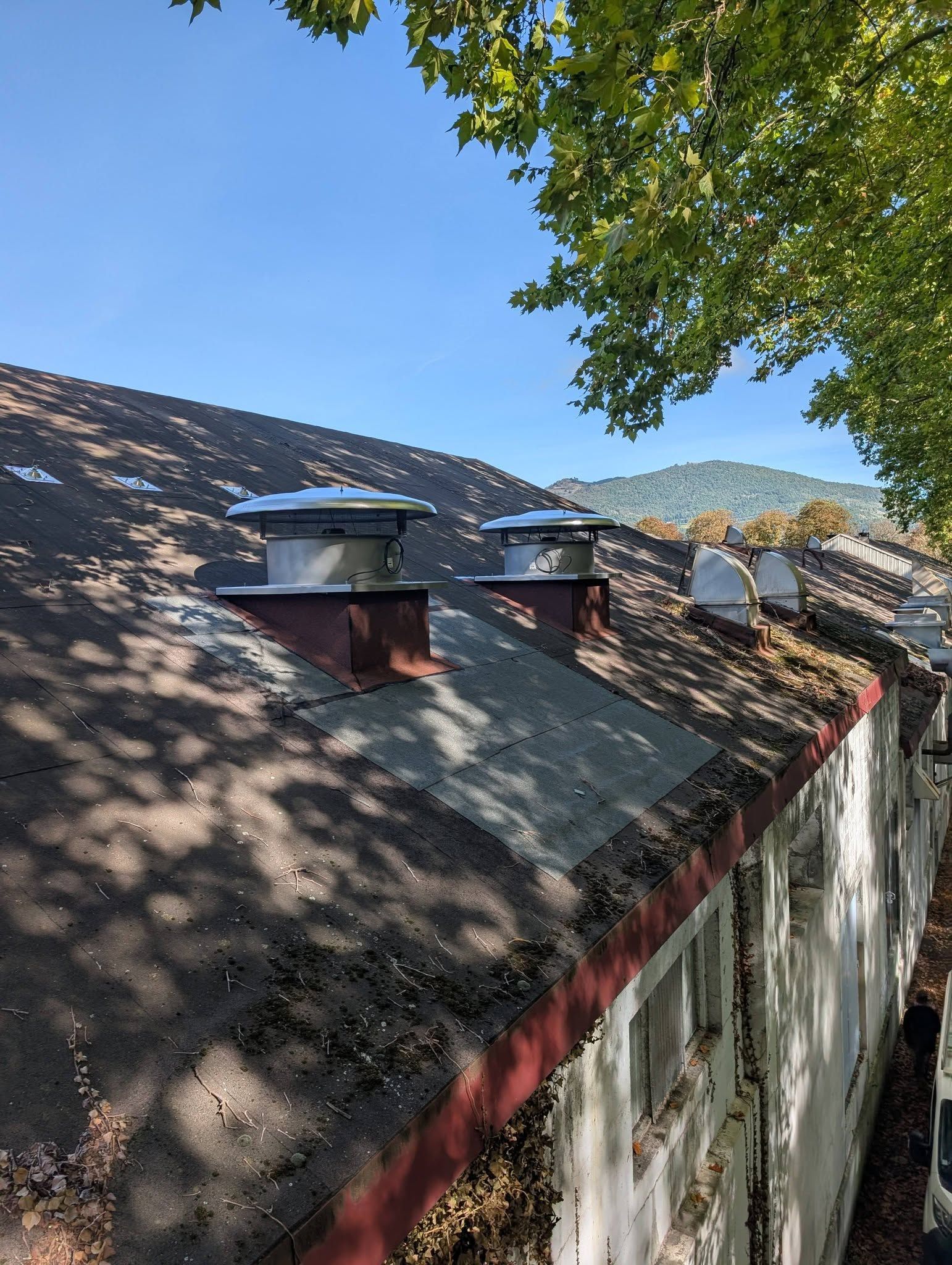Un toit avec plusieurs conduits de cheminée métalliques.
