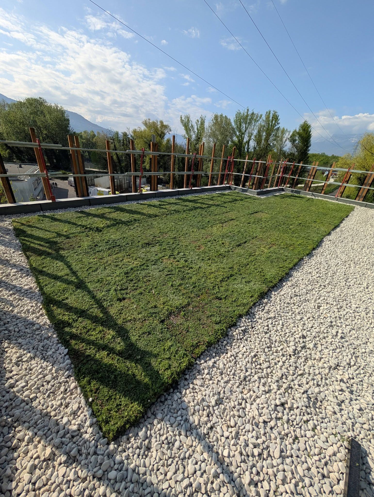 Une toiture-terrasse végétalisée, recouverte de graviers et de gazon.