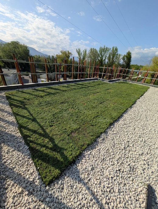 Une toiture-terrasse végétalisée, recouverte de graviers et de gazon.