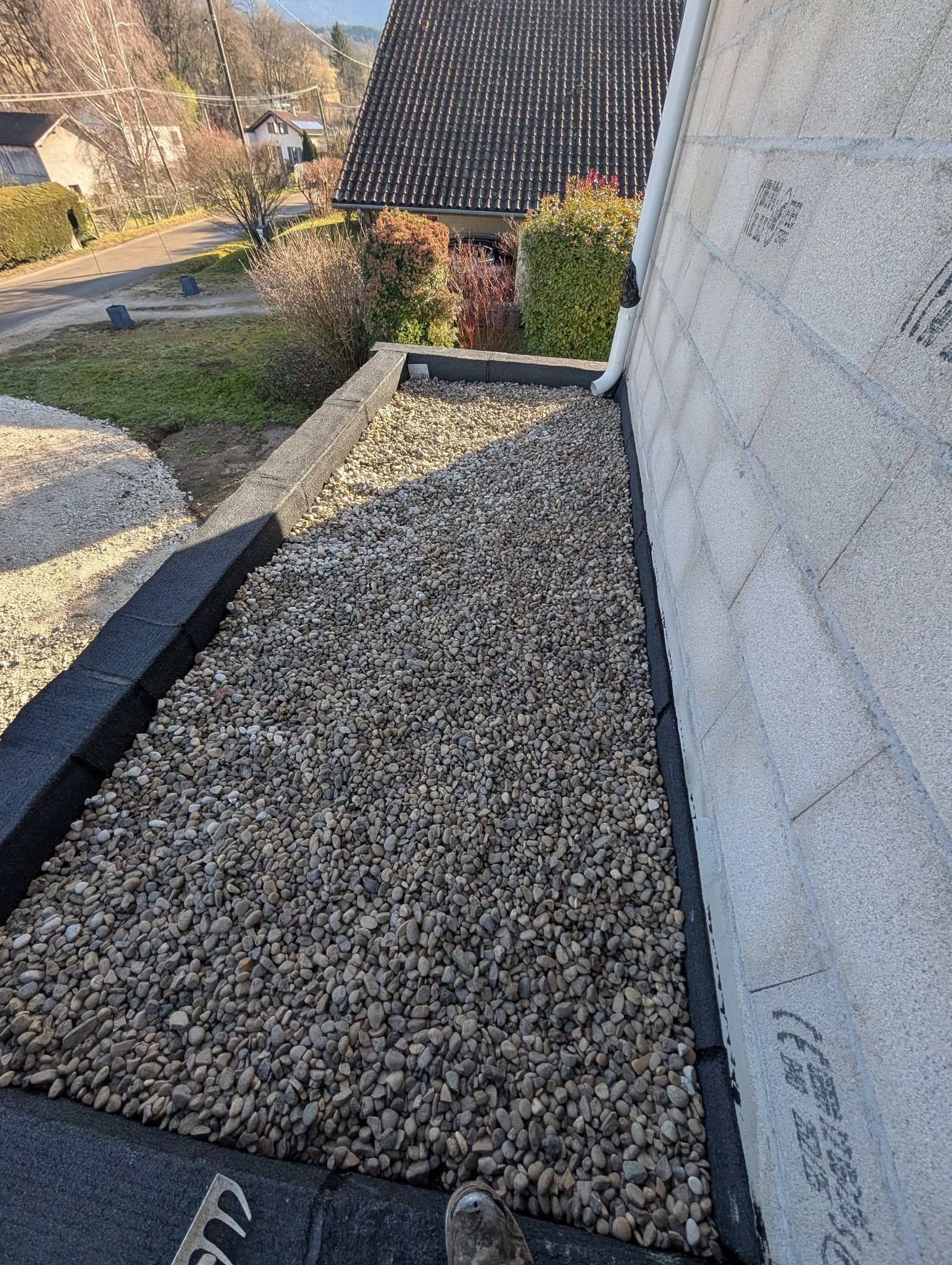 Une section de toit plate, remplie de gravier, bordée d'un cadre noir.