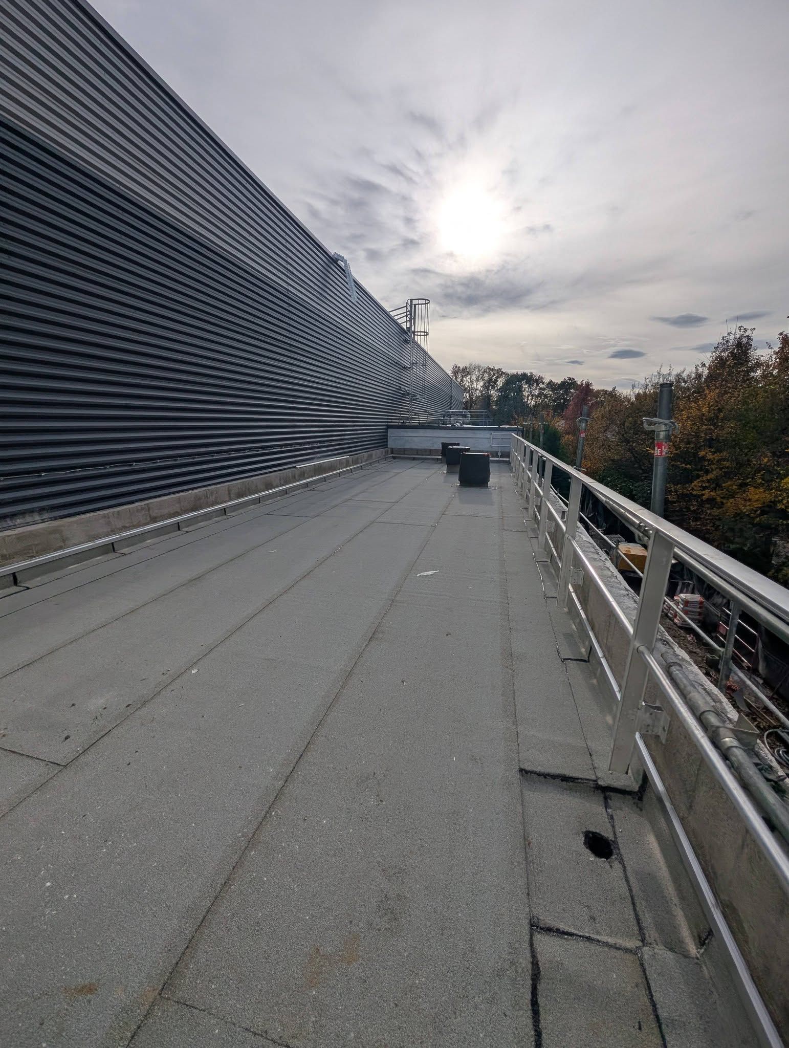 Une terrasse plate, recouverte d'une membrane d'étanchéité bitumineuse, accolée à un bâtiment professionnel.