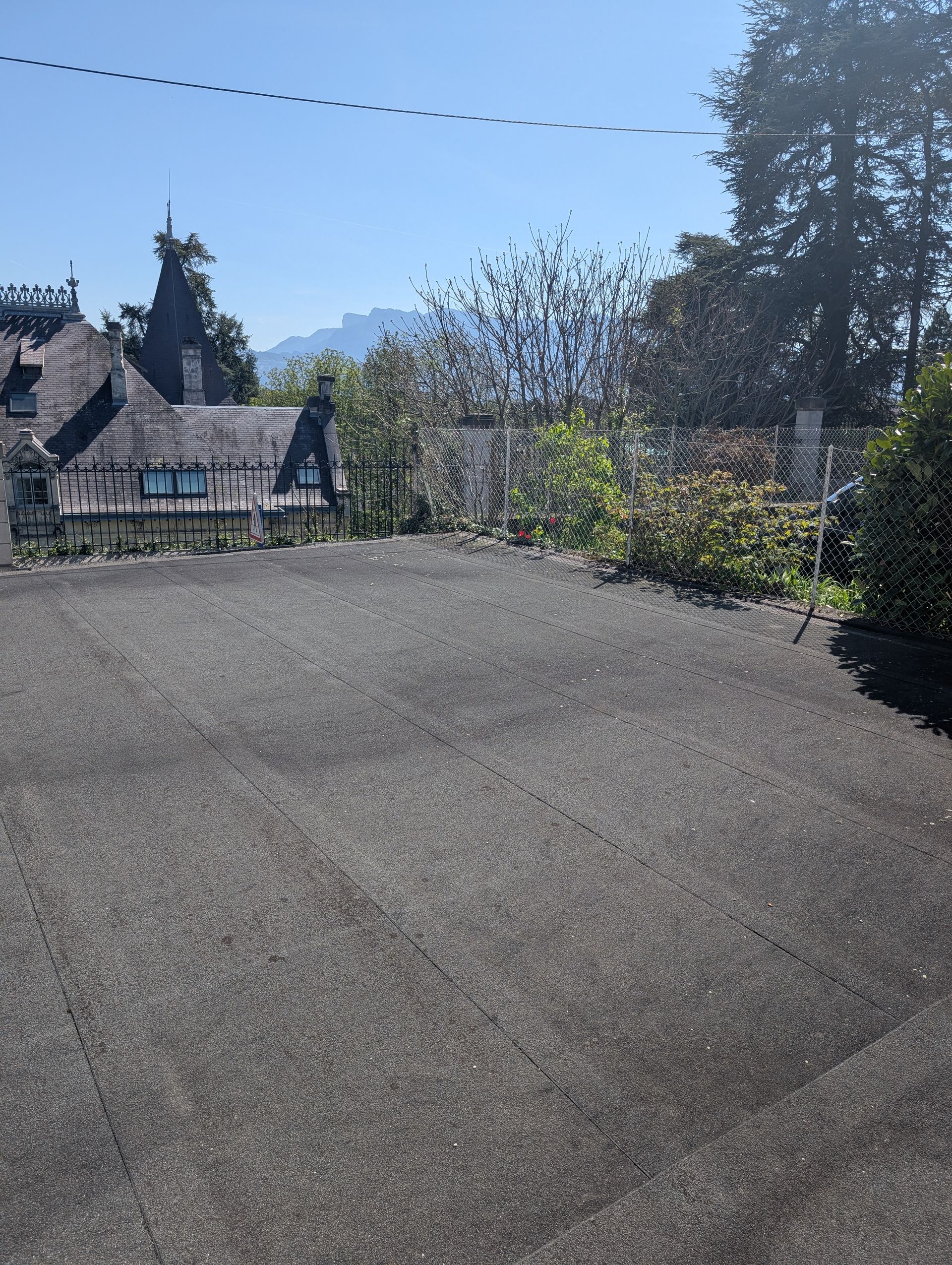 Une toiture plate recouverte de bitume chauffé, avec vue sur une maison.
