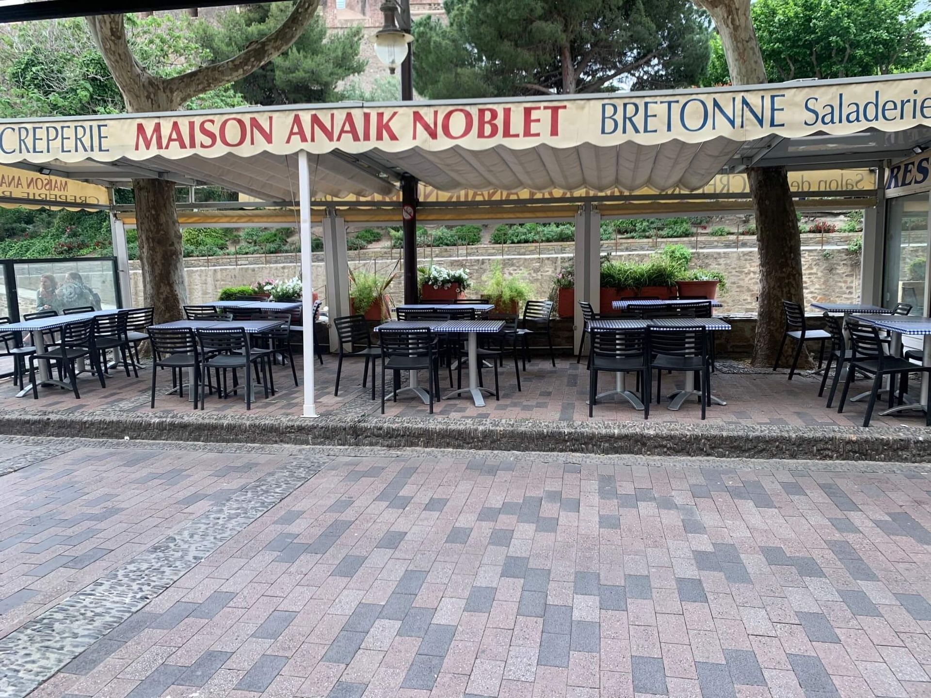Restaurant en plein air avec tables et chaises sous un auvent.