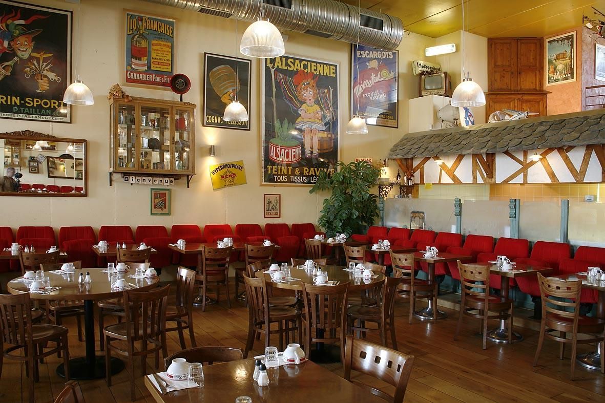 Intérieur du restaurant avec des banquettes rouges, des tables en bois et des affiches vintage aux murs.
