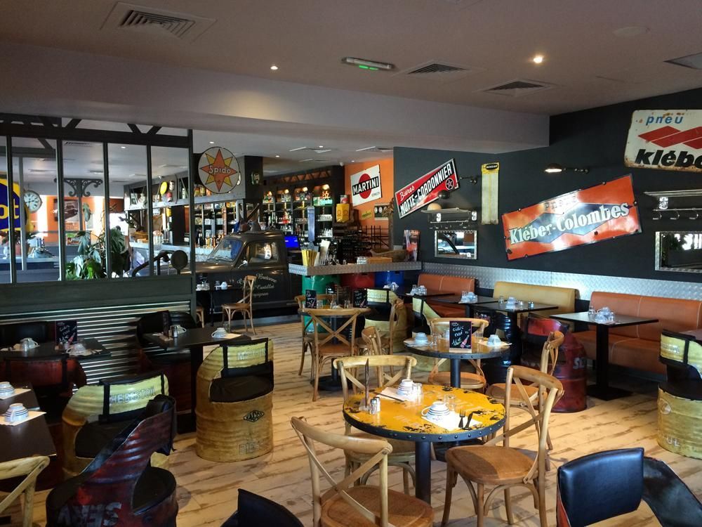 Intérieur avec tables et chaises. La décoration comprend des panneaux et des sièges fabriqués à partir de tonneaux recyclés.