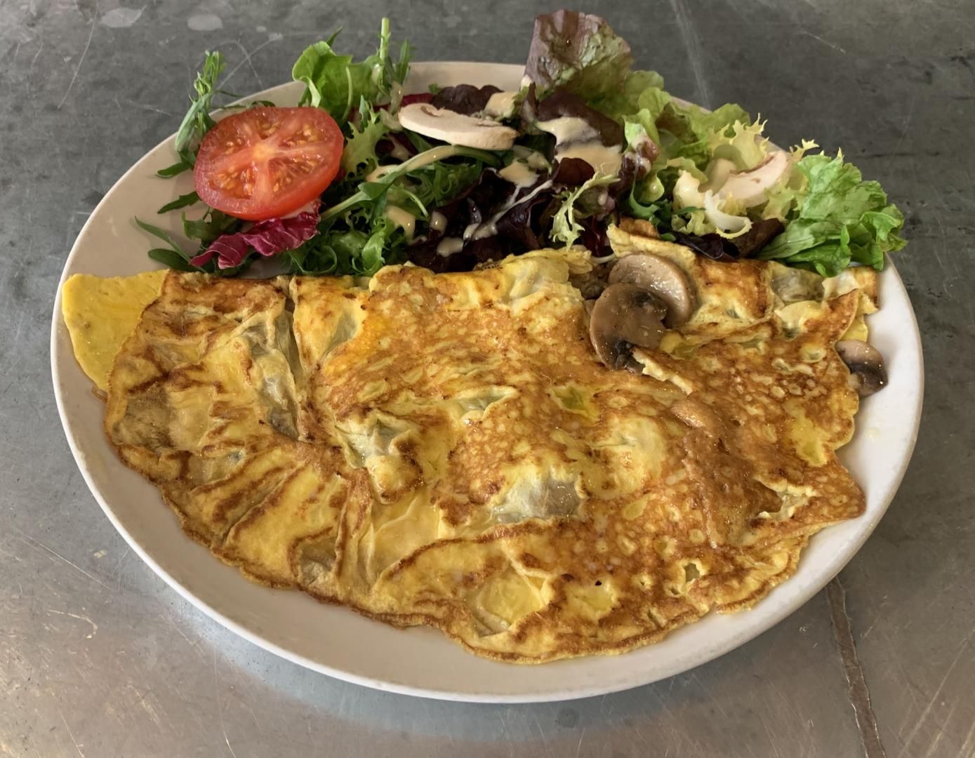 Omelette aux champignons et salade d'accompagnement sur une assiette blanche.