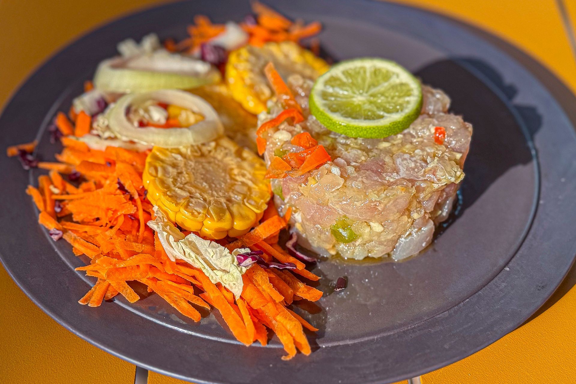 Assiette de tartare de thon avec maïs, carottes, oignon et citron vert.