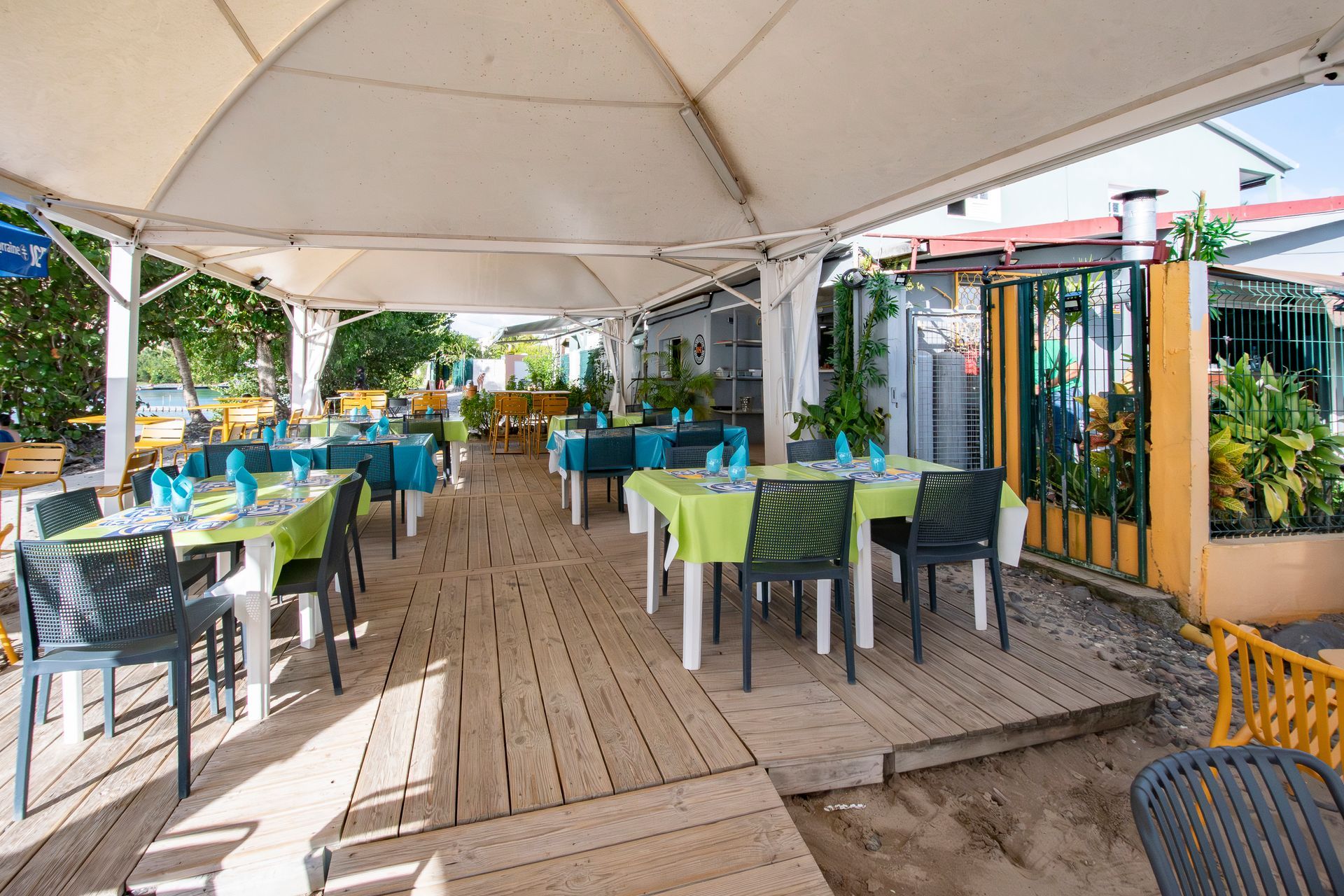 Restaurant en plein air avec des tables dressées pour dîner, sous un auvent blanc.