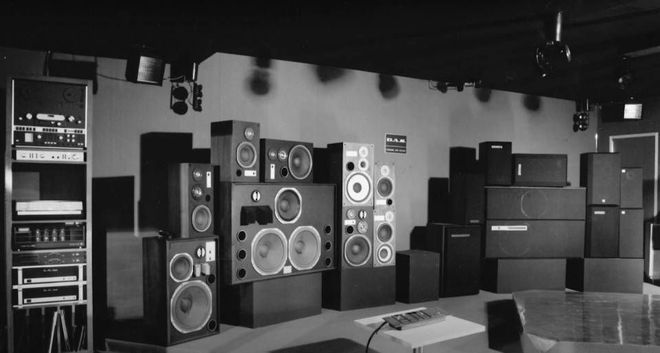 Schwarz-weisse Bühne mit gestapelten Lautsprecherboxen und Audiogeräten in einem Musikclub