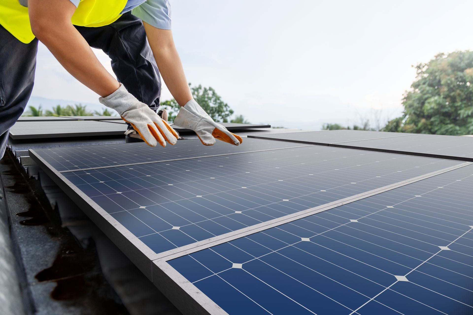 Un ouvrier portant un gilet de sécurité jaune installe un panneau solaire sur un toit.