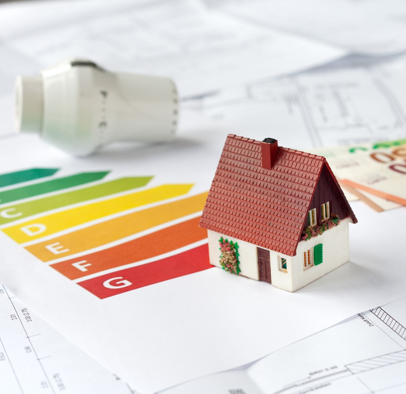 Concept d’efficacité énergétique avec maquette de maison, ampoule, calculatrice et tableau d’évaluation à code couleur