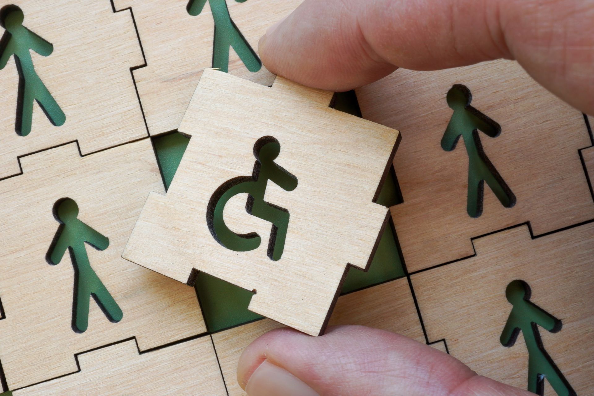 Pièce de puzzle en bois avec le dessin d'un bonhomme sur un fauteuil roulant